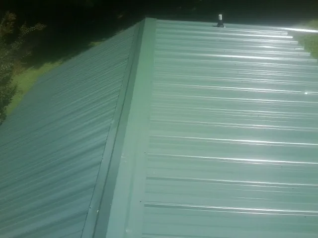 New green metal panels meeting at the ridge of a roof — Flat Roof Repair work by our crew in Albertson
