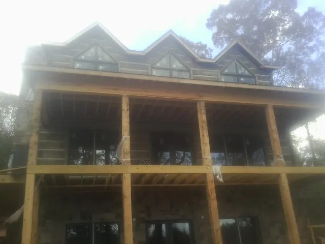 Dormers and porch framing on a large log home under construction — Roof Coating work by our crew in Albertson